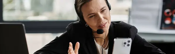 A middle-aged woman in distress listens with a headset at a desk. — Stock Photo