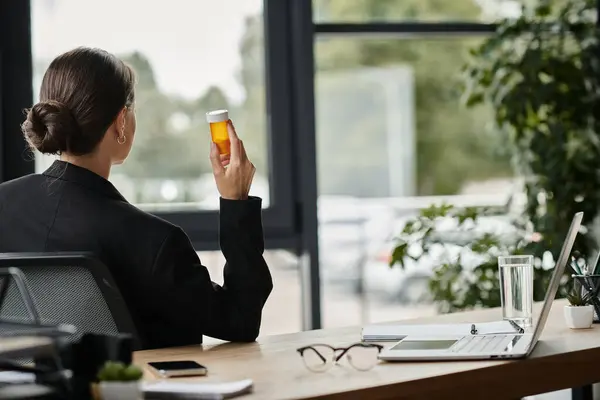 Middle-aged woman in a business suit holding a bottle of medicine. — Stockfoto