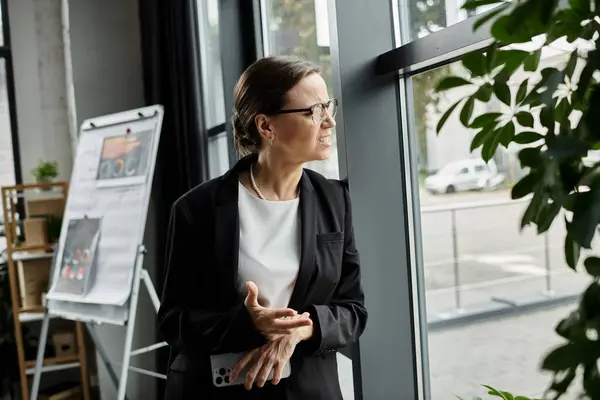 Depressed business woman standing by office window, overwhelmed by stress. — стоковое фото