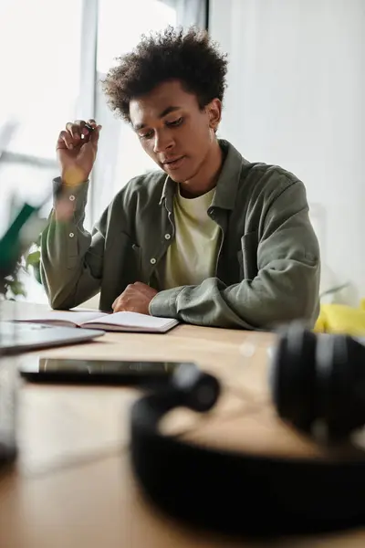 Young man engrossed in studying with headphones and notebook on desk. — Photo de stock