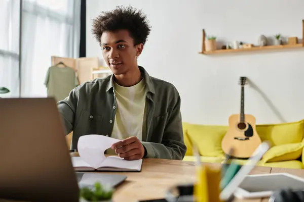 A young man, African American, sits at a desk with a laptop, engrossed in online studying. — Stockfoto