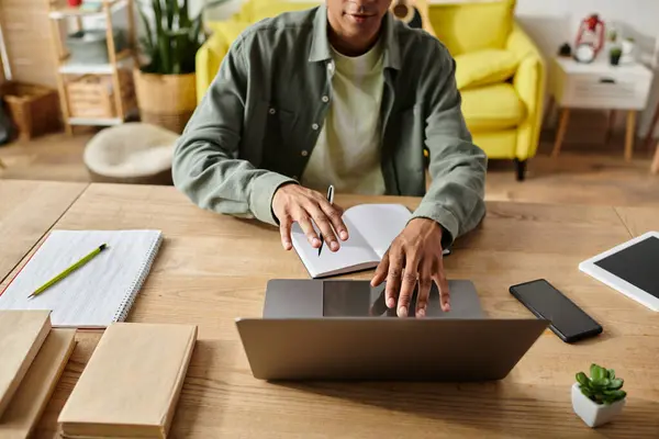A man immersed in work, sits at a table typing on a laptop. — Stock Photo