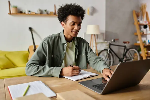 Young man engrossed in online study on laptop at home desk. — Stockfoto