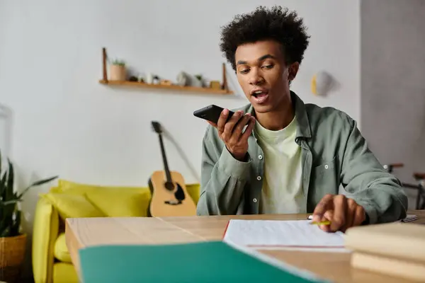 A young man talks on his phone while seated at a table. — Stock Photo