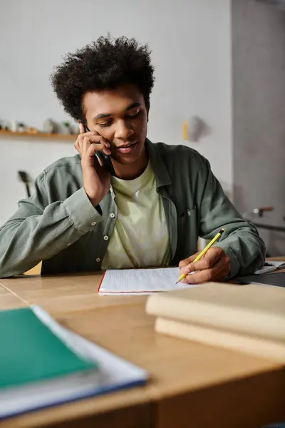 Young man multitasking on the phone and at a desk. — Stock Photo