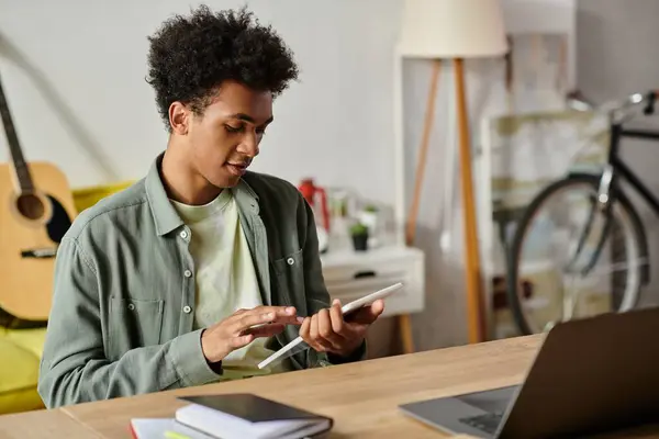 A young African American man studying online with a laptop and a tablet at a table. — Stock Photo