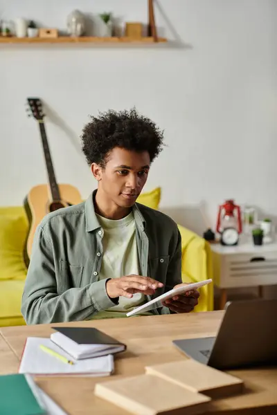 Young African American man focusing on laptop screen while studying at home. — Stockfoto