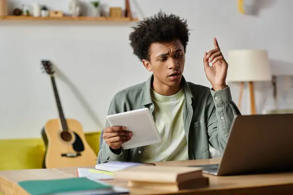 A man, immersed in online study, sits at a table with a laptop open in front of him. — Foto stock