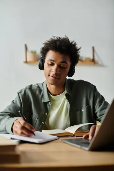 A young man immersed in online learning, sitting at a desk with headphones and a laptop. — Stock Photo