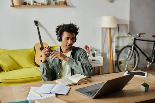 An African American man sitting at a table with a laptop and a book. — Stock Photo