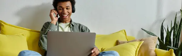 A young African American man studying online with a laptop on his lap. — Stockfoto