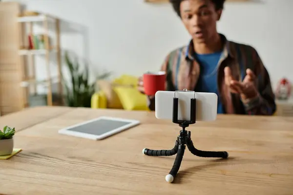 Young African American male blogger recording himself on phone on tripod. — Stock Photo