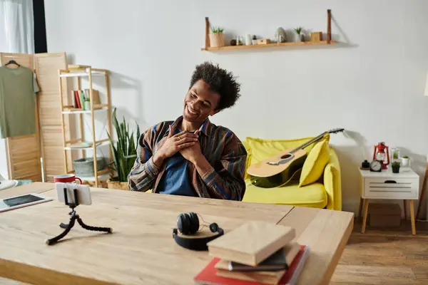 A young man is sitting at a desk, working on his phone and talking on the phone. — Foto stock