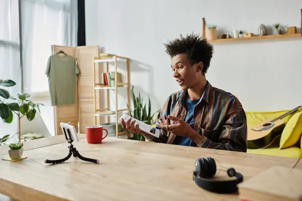 Young man, African American, blogs on phone camera at table. — Stock Photo