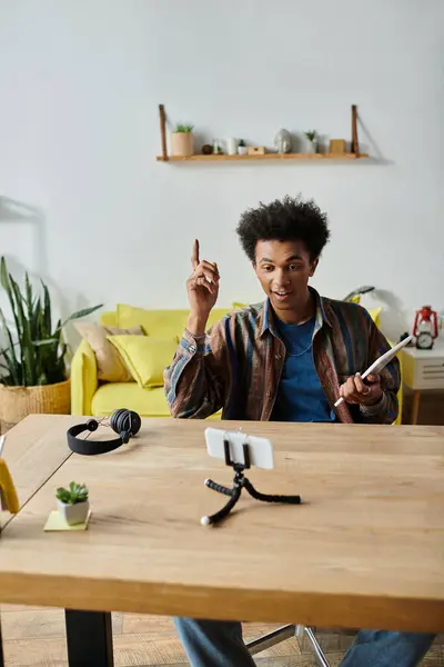 A young African American male blogger using a tablet and talking on the phone. — стокове фото