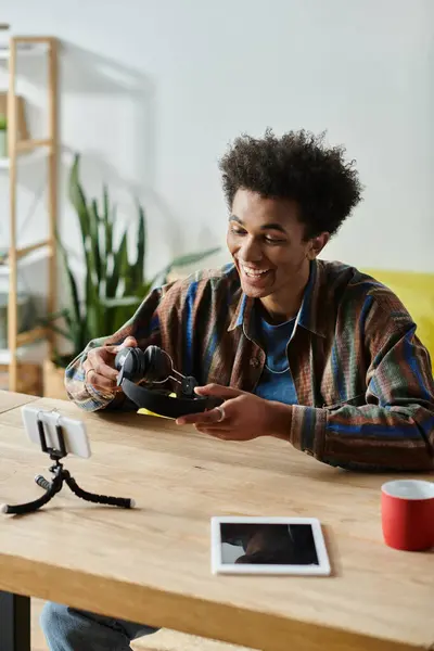 A young African American man busy with his tablet and phone, multitasking as a content creator. — Foto stock