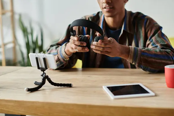 Young African American male blogger with headphones, using a tablet at a table. — Stock Photo