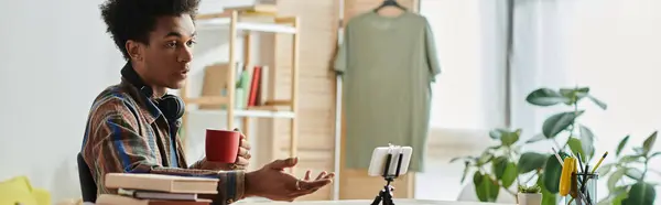 Young African American blogger on phone camera at desk with coffee. — Foto stock