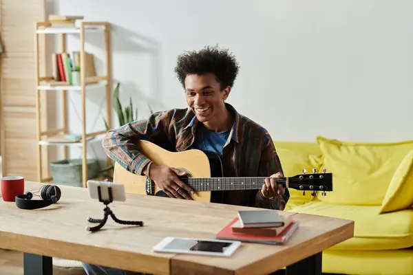 A young man strums his acoustic guitar in a cozy living room. - foto de stock