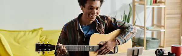 Talented young man creating music with acoustic guitar in his cozy living room. — стоковое фото