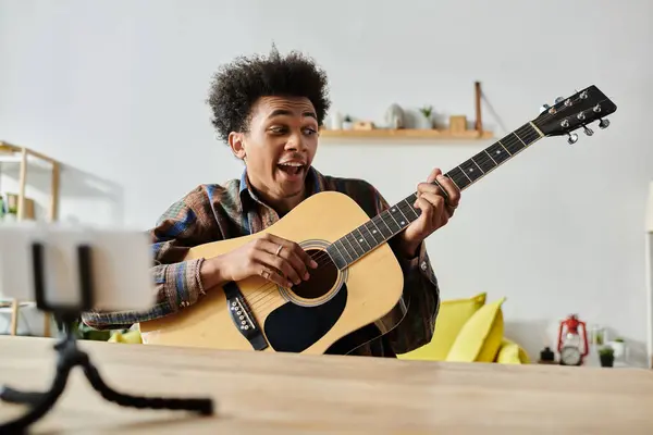 Young man plays acoustic guitar in living room. - foto de stock