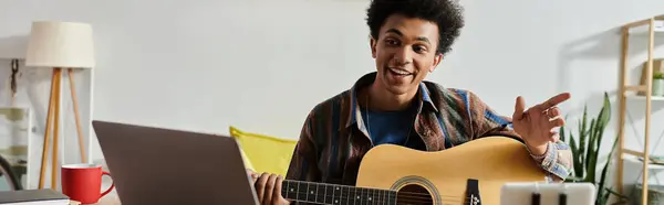 A young man playing acoustic guitar in front of a phone while immersed in music. — Stock Photo