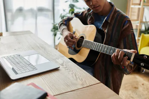 A man serenades with an acoustic guitar in front of a phone. - foto de stock
