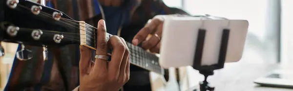 Talented musician strums an acoustic guitar in front of a camera. — стокове фото