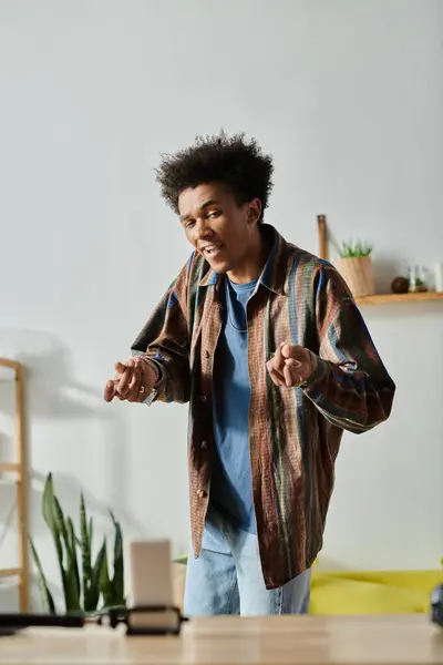 A young African American man, standing in front of a television, speaks to a phone camera. — Stock Photo