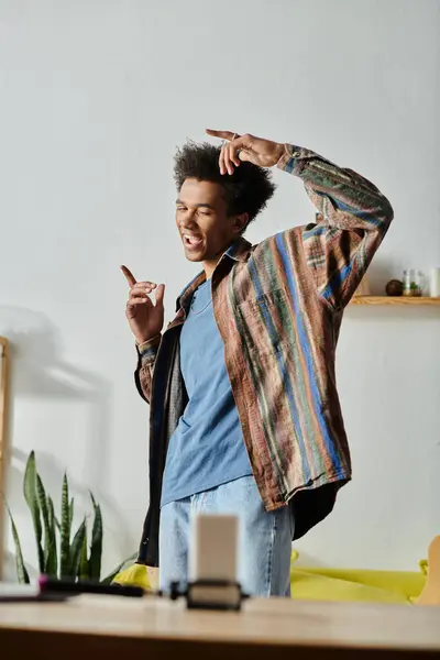 Young African American male blogger standing in living room with hands in pockets, talking on phone camera. — Foto stock