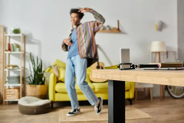 A young African American male blogger stands in a living room, working on a phone while talking on his phone camera. — стокове фото