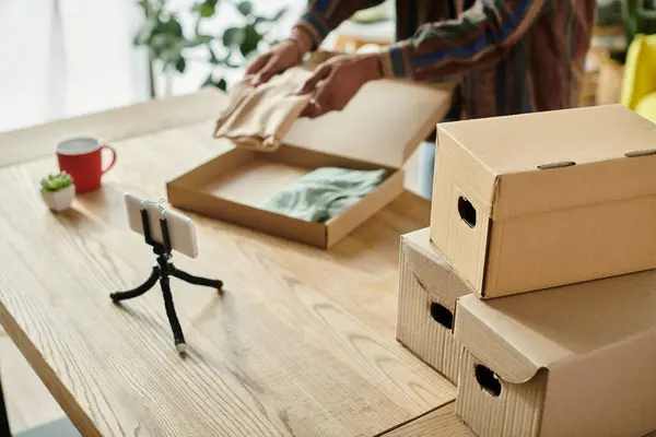 A young African American male blogger talks on the phone while placing boxes on a table. — Stockfoto