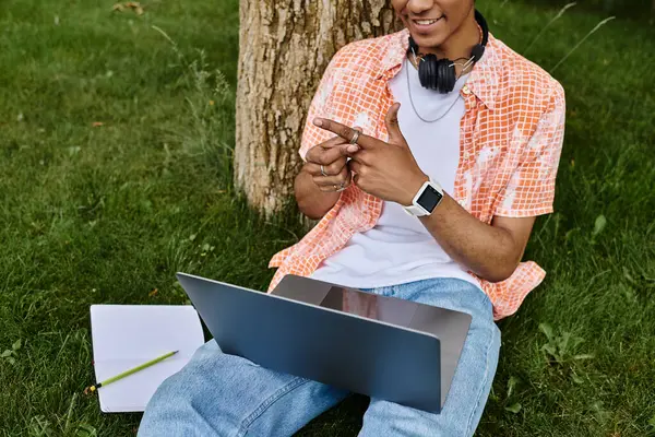 Young man with laptop under tree in park. — Stock Photo