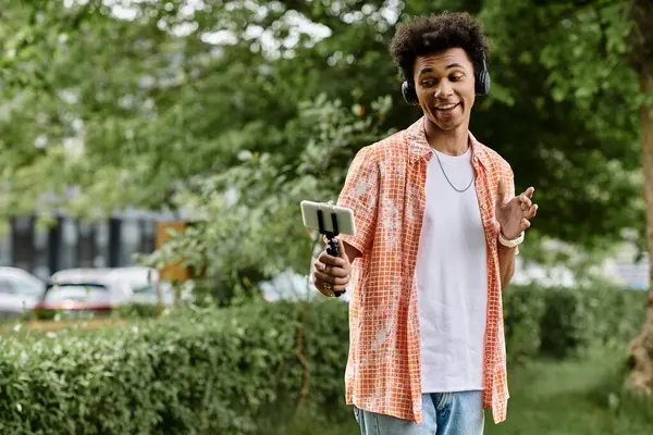A young African American man lost in his phone amidst the serene park surroundings. — Stock Photo
