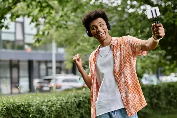 A young African American man happily taking a selfie in a vibrant park setting. — Stock Photo