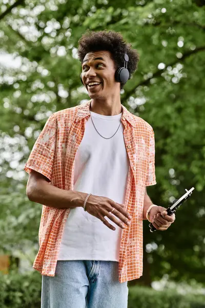 A young man with headphones walks in the park. — стокове фото
