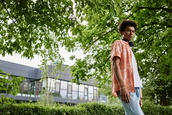 Young man of African American descent standing in park near building. — Fotografia de Stock
