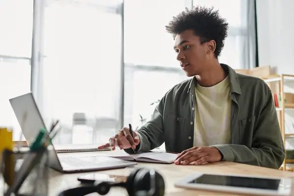 A young man, African American, focused and productive, works diligently on his laptop in a contemporary office space. — Stock Photo