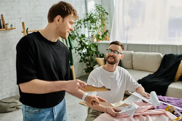 Two men, both designers, collaborating on trendy attire in their workshop. — Stock Photo