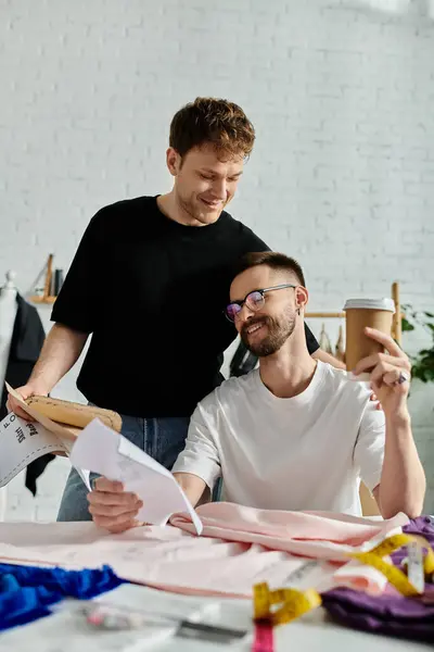 Two men in love, creatively collaborating over a piece of paper at a stylish table. — Stock Photo