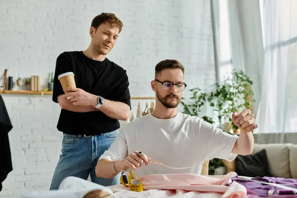 Two men, a gay couple, sit at a table in a designer workshop, passionately creating trendy attire. — Stock Photo