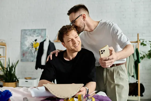 Gay l'homme baisers tête de copain dans un designer atelier collaborant sur la création à la mode tenue ensemble. — Photo de stock