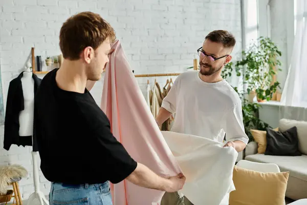 Two men, a gay couple, standing side by side in a designer workshop, collaborating on creating trendy attire. — Stock Photo