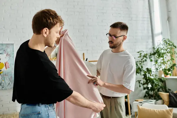 Two fashion designers, a gay couple, stand together in their designer workshop, immersed in creating trendy attire. — Stock Photo