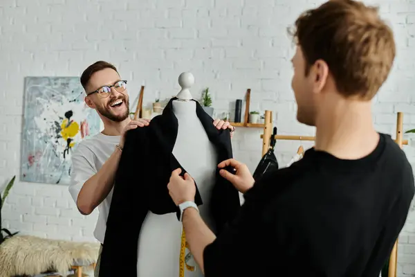 A man and mannequin hold a black shirt, working in a designer workshop. — Stock Photo
