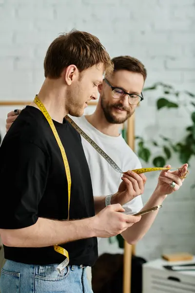 Two men, partners in both love and design, collaborate on creating cutting-edge attire in a designer workshop. — Stock Photo