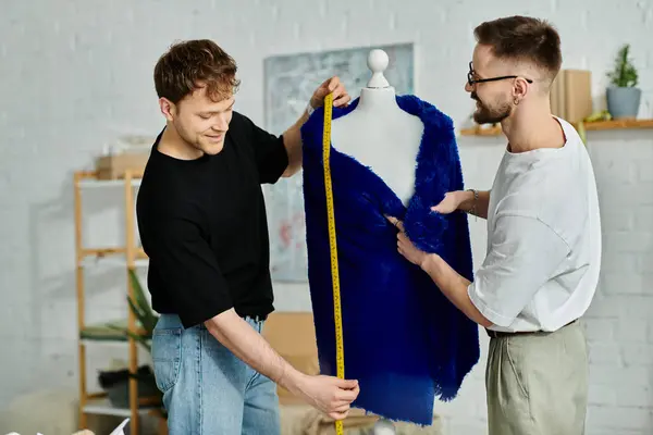 Two men, a gay couple, stand beside a mannequin in a designer workshop creating trendy attire. — Stock Photo