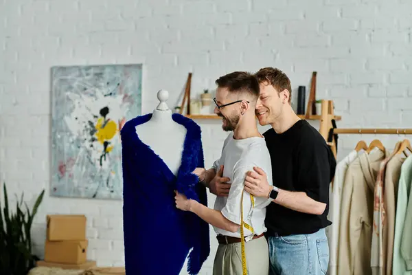 Two men stand beside a mannequin, collaborating on trendy attire in a designer workshop. — Stock Photo