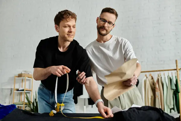 A gay couple in love, collaborating on trendy attire in a designer workshop. — Stock Photo