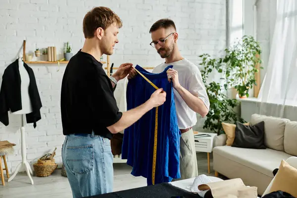 Two men, a gay couple, stand side by side in a designer workshop, working on trendy attire. — Stock Photo
